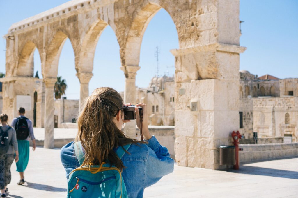 pexels-photo-2087391-2087391-1 A tourist photographs the ancient stone arches in Jerusalem's Old Town, capturing the essence of travel and history.
